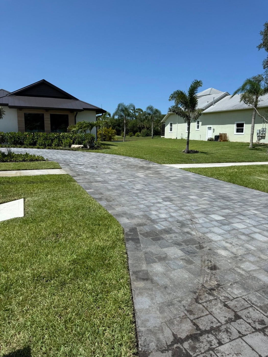 Curved silver paver walkway between two homes