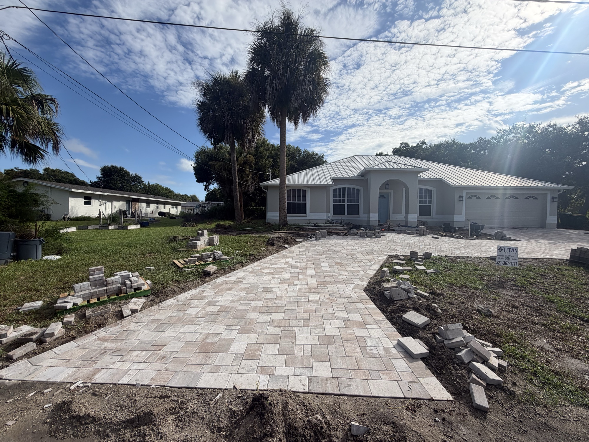 Paver walkway leading to the front entry between palms