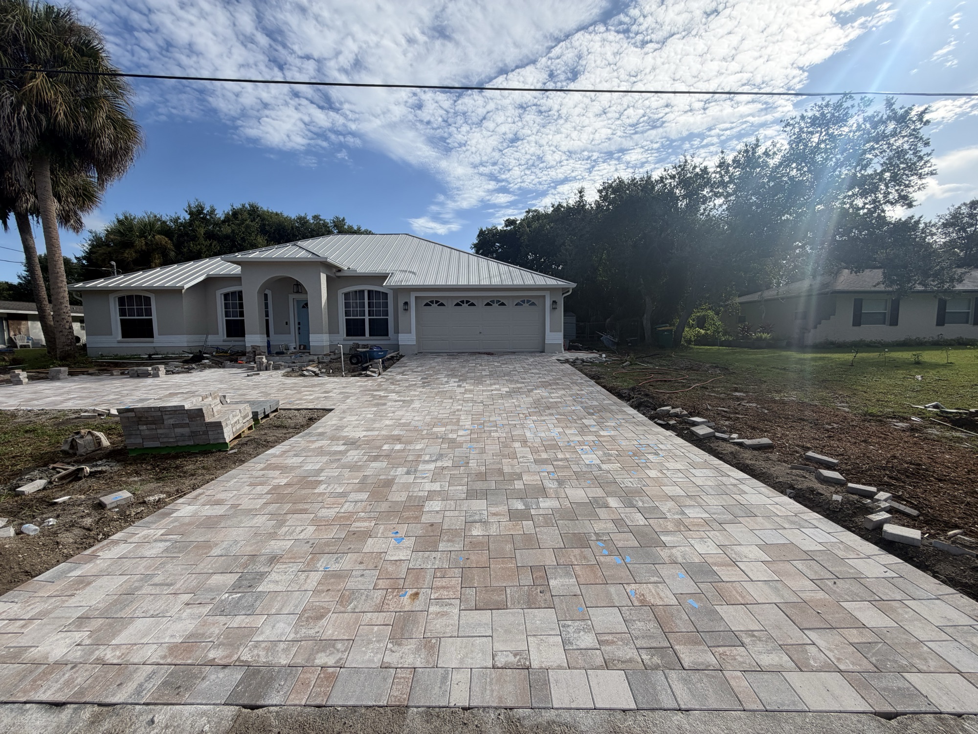 Straight-on view of a long paver driveway to a two-car garage